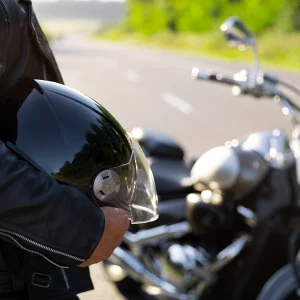 Sosteniendo el casco y delante de la moto